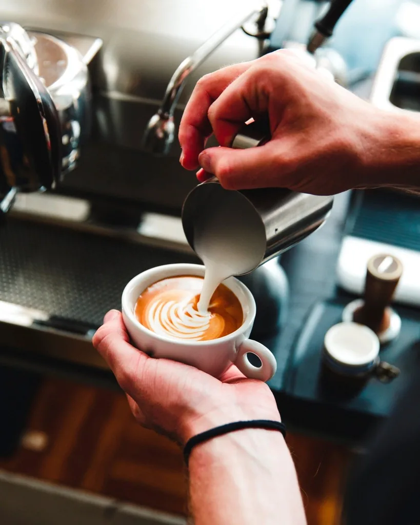 A barista pouring latte art at the espresso machine