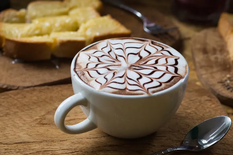 A mocha with chocolate-sauce latte art in a white cup